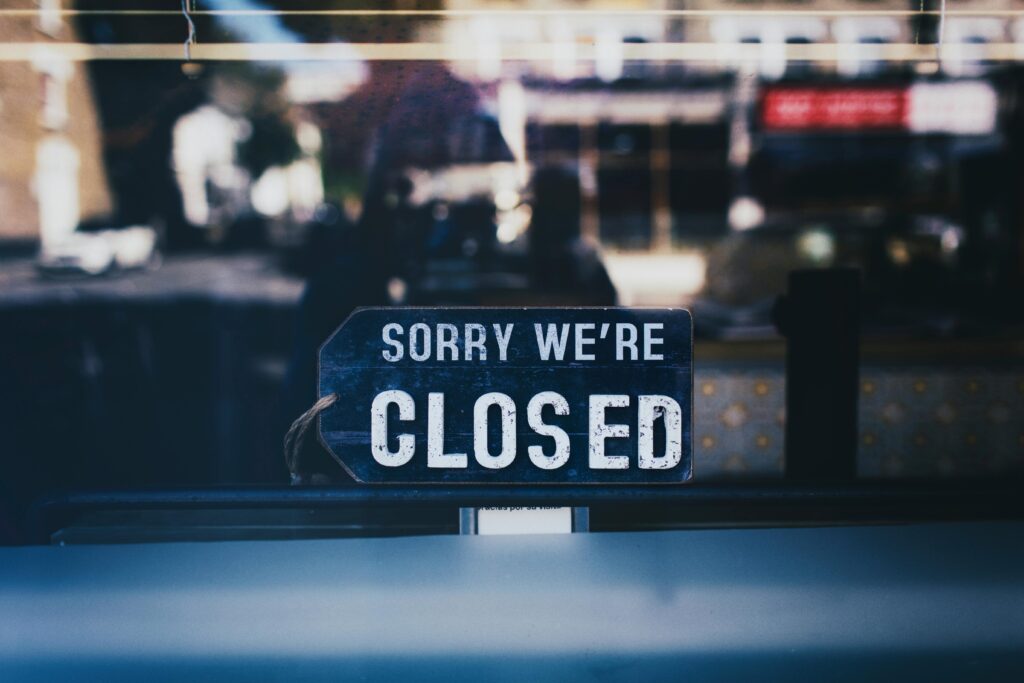 Moody image capturing a 'Sorry We're Closed' sign in a London shop window.