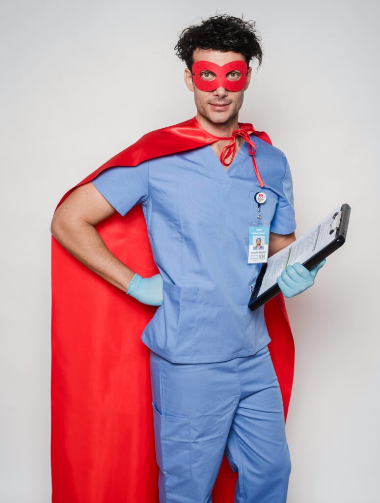 A healthcare professional dressed as a superhero with a red cape and mask in a studio setting.
